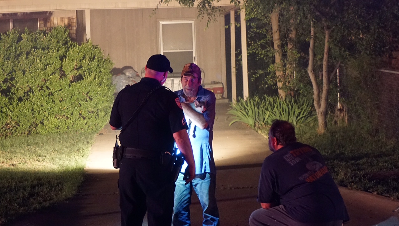 Police transfer the house occupants two cats back him after firefighters saved them from inside the house. (LIVE! Photo/John Basquez)