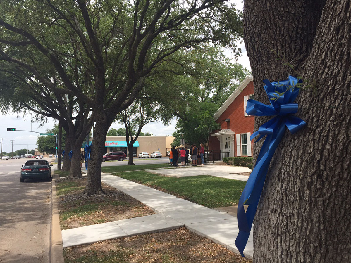 A blue ribbon is wrapped around an Oak tree in front of Johnson’s Funeral Home in remembrance of Police Sgt. Korby Kennedy. (LIVE! Photo/Amanda Henson)
