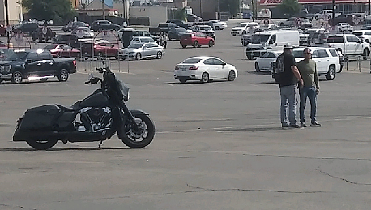 One of the two males to the right of the motorcycle confronted the mysterious bus's driver. One of the two males to the right of the motorcycle confronted the mysterious bus's driver.