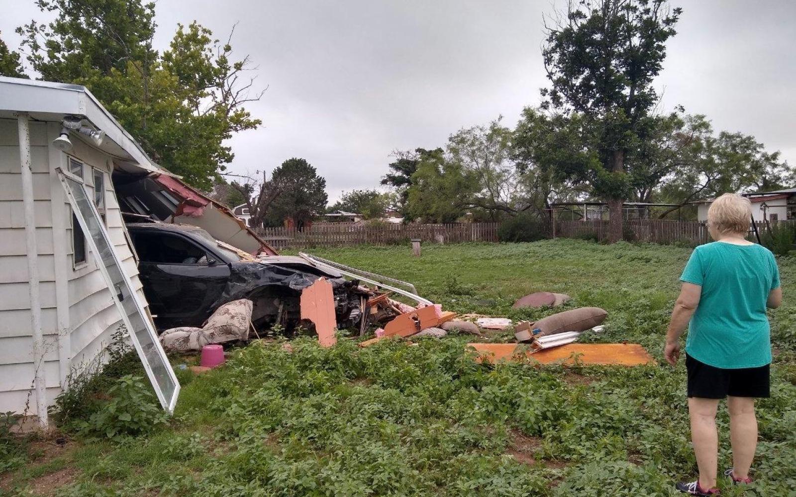 Jennifer Byrd surveys the damage cause by the black 2016 Dodge Charger that crashed all the way through their house and into the backyard on July 11, 2021. 