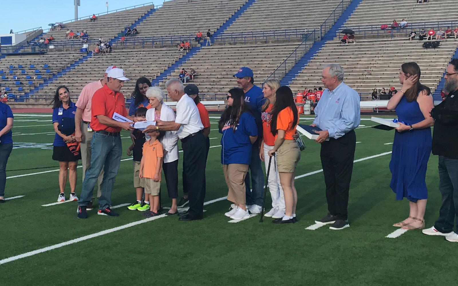 School Board Trustee Ami Mizell-Flint (far left), Superintendent Chris Moran, San Angelo ISD administratos, State Rep. Drew Darby, and Rep. August Pfluger's District Director Karin Kuykendall (second from right), and VA official and Concho Calley veterans' advocate Luis Martinez (far right) watch as San Angelo ISD Board of Trustees President Dr. Taylor Kingman present Mr. Manuel Gonzales with a high school diploma.