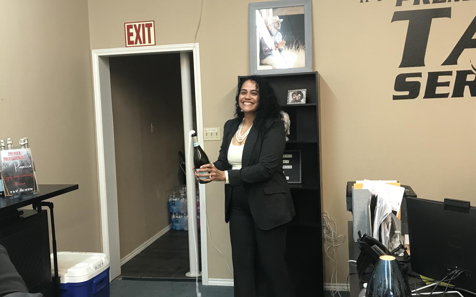 Premier Tax Service owner Diana Ellison pops a bottle of champagne in celebration of her company's five-year anniversary Wednesday, Jan. 22, 2025.