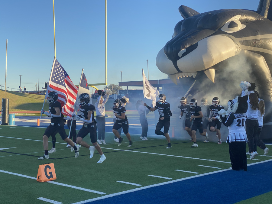 Water Valley's Landon Lacy (6) helps lead the Wildcats onto the field while carrying a flag.