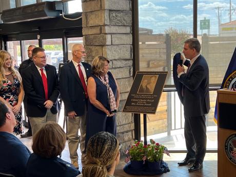 VA Director Keith Bass (right) unveils the plaque that will be affixed to the outside of the building in honor of Col. Charles and JoAnne Powell to the Powell's family. From left: Caitlin McKinney, Dr. Colin McKinney, Jerry and Terri McKinney.