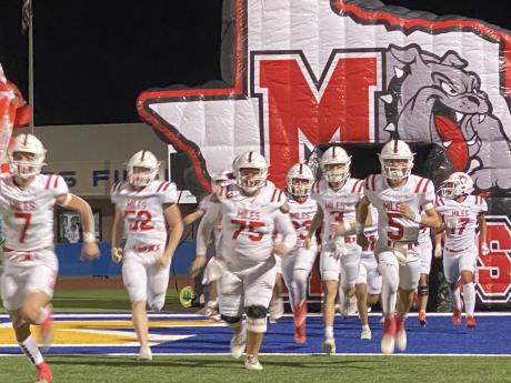 The Miles Bulldogs charge onto the field before their first-round playoff game against Lindsay on Thursday, Nov. 14, 2024.