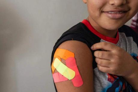 Omar Wahidi, 12, shows bandages from vaccines given to him in his right arm.