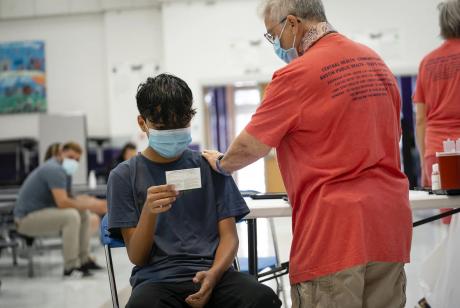 Johan Arzade, 12, looks at his COVID-19 vaccination record card after receiving a dose of the Pfizer vaccine at a clinic organized by the Travis County Mobile Vaccine Collaborative at Rodriguez Elementary School in Austin on July 28, 2021.