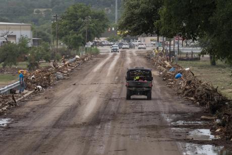 Emergency vehicles cross the debris-covered San Antonio Street bridge in Center Point, on July 16, 2026, after floodwaters from the Guadalupe River overtook it that morning.
