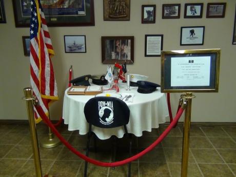 Various awards, medals and photographs populate the wall space, and the POW MIA chair is focused upon (LIVE! photo by Cheyenne Benson)