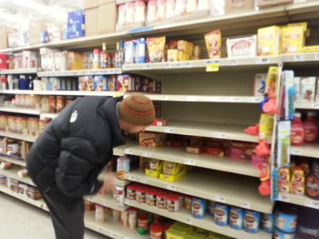 A man in search of a box of cocoa peers to the back of an empty shelf at H-E-B. (LIVE! Photo by Chelsea Schmid)
