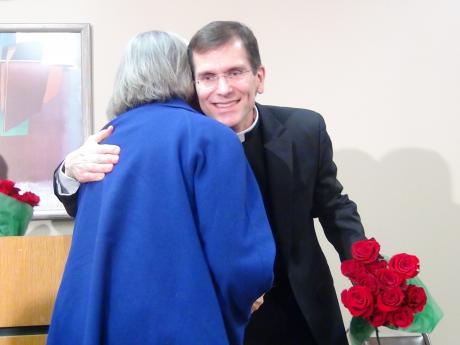 Michael Sis hugs a woman on Thursday morning after welcoming his new flock. (LIVE! Photo by Cheyenne Benson)