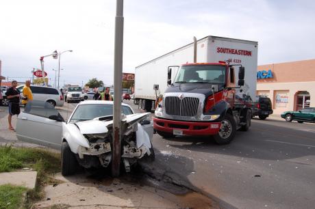 A semi-truck remains untouched in the inside lane, having pulled into the outer lane causing a compact car to swerve and hit a light pole. (LIVE! Photo by Chelsea Schmid)
