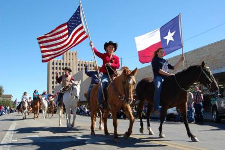 Two riders carrying the Texas and American flags bring in the Veterans Day Parade. (LIVE! Photo by Chelsea Schmid)