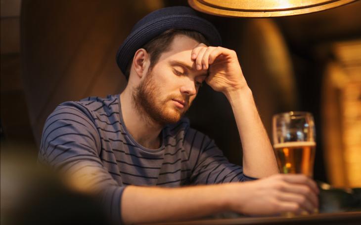 Unhappy lonely man drinking beer at bar or pub