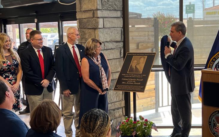 VA Director Keith Bass (right) unveils the plaque that will be affixed to the outside of the building in honor of Col. Charles and JoAnne Powell to the Powell's family. From left: Caitlin McKinney, Dr. Colin McKinney, Jerry and Terri McKinney.