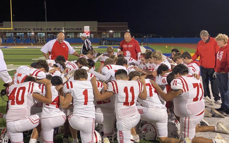 The Miles Bulldogs football team prays before its first-round playoff game against Lindsay in Brock on Thursday, Nov. 14, 2024.