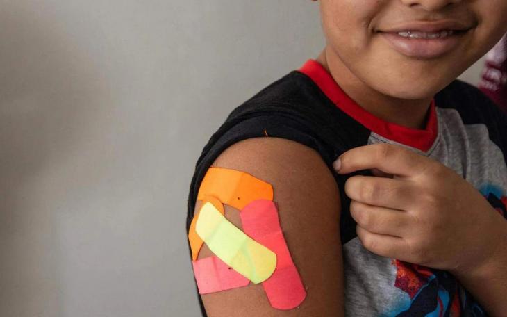 Omar Wahidi, 12, shows bandages from vaccines given to him in his right arm.