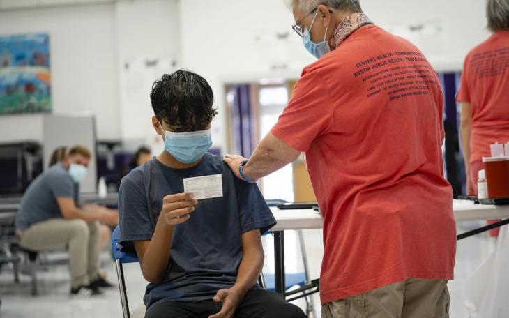 Johan Arzade, 12, looks at his COVID-19 vaccination record card after receiving a dose of the Pfizer vaccine at a clinic organized by the Travis County Mobile Vaccine Collaborative at Rodriguez Elementary School in Austin on July 28, 2021.