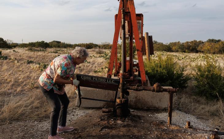 Jackie Chesnutt props up a sign next to a leaking oil well operated by CORE Petro on her property near Knickerbocker on Nov. 18, 2025.