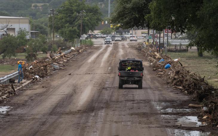 Emergency vehicles cross the debris-covered San Antonio Street bridge in Center Point, on July 16, 2026, after floodwaters from the Guadalupe River overtook it that morning.
