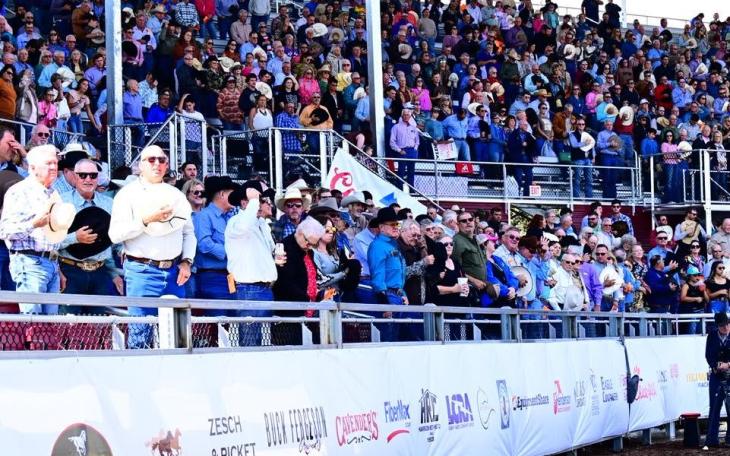 The crowd stands for the national anthem during the Cinch Roping Fiesta.