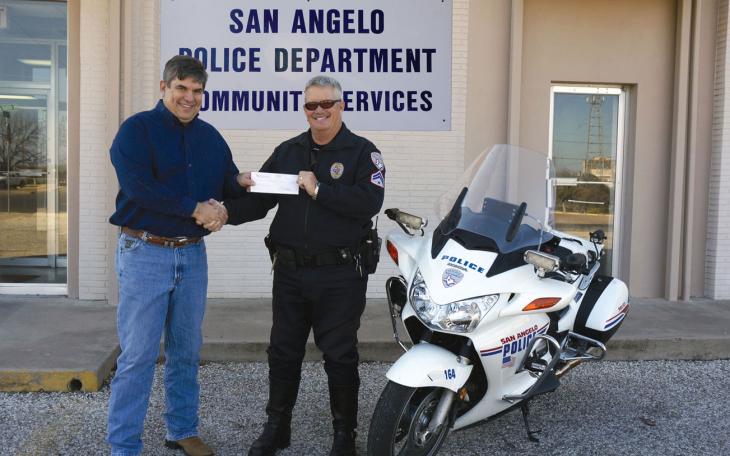 Joe Hyde, publisher of San Angelo LIVE!, gives a check for $500, donating to the Blue Santa program headed by Officer Brian Bylsma. (LIVE! Photo/John Basquez)