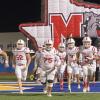 The Miles Bulldogs charge onto the field before their first-round playoff game against Lindsay on Thursday, Nov. 14, 2024.