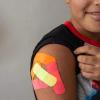 Omar Wahidi, 12, shows bandages from vaccines given to him in his right arm.