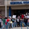 Students from San Antonio's Memorial High School walk out in protest against Immigration and Customs Enforcement (ICE) on Jan. 30, 2026. School staff and Edgewood ISD police officers blocked access to public sidewalks and the road in front of the campus saying that school property was extended for student safety. Students were directed back to class after the brief demonstration.