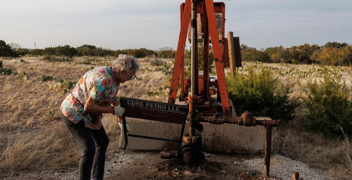 Jackie Chesnutt props up a sign next to a leaking oil well operated by CORE Petro on her property near Knickerbocker on Nov. 18, 2025.