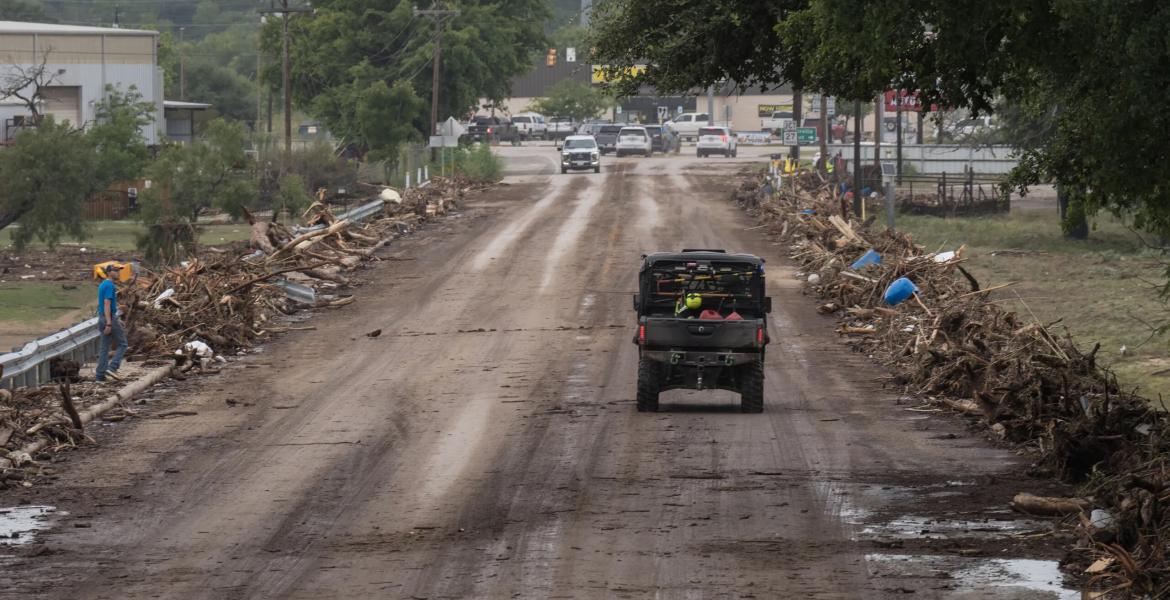 Emergency vehicles cross the debris-covered San Antonio Street bridge in Center Point, on July 16, 2026, after floodwaters from the Guadalupe River overtook it that morning.