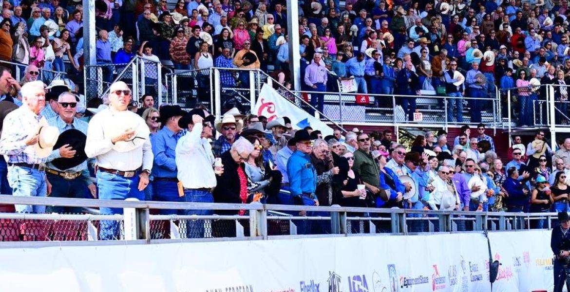 The crowd stands for the national anthem during the Cinch Roping Fiesta.