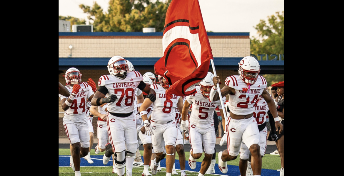 The Carthage football team runs onto the field during the 2026 season.